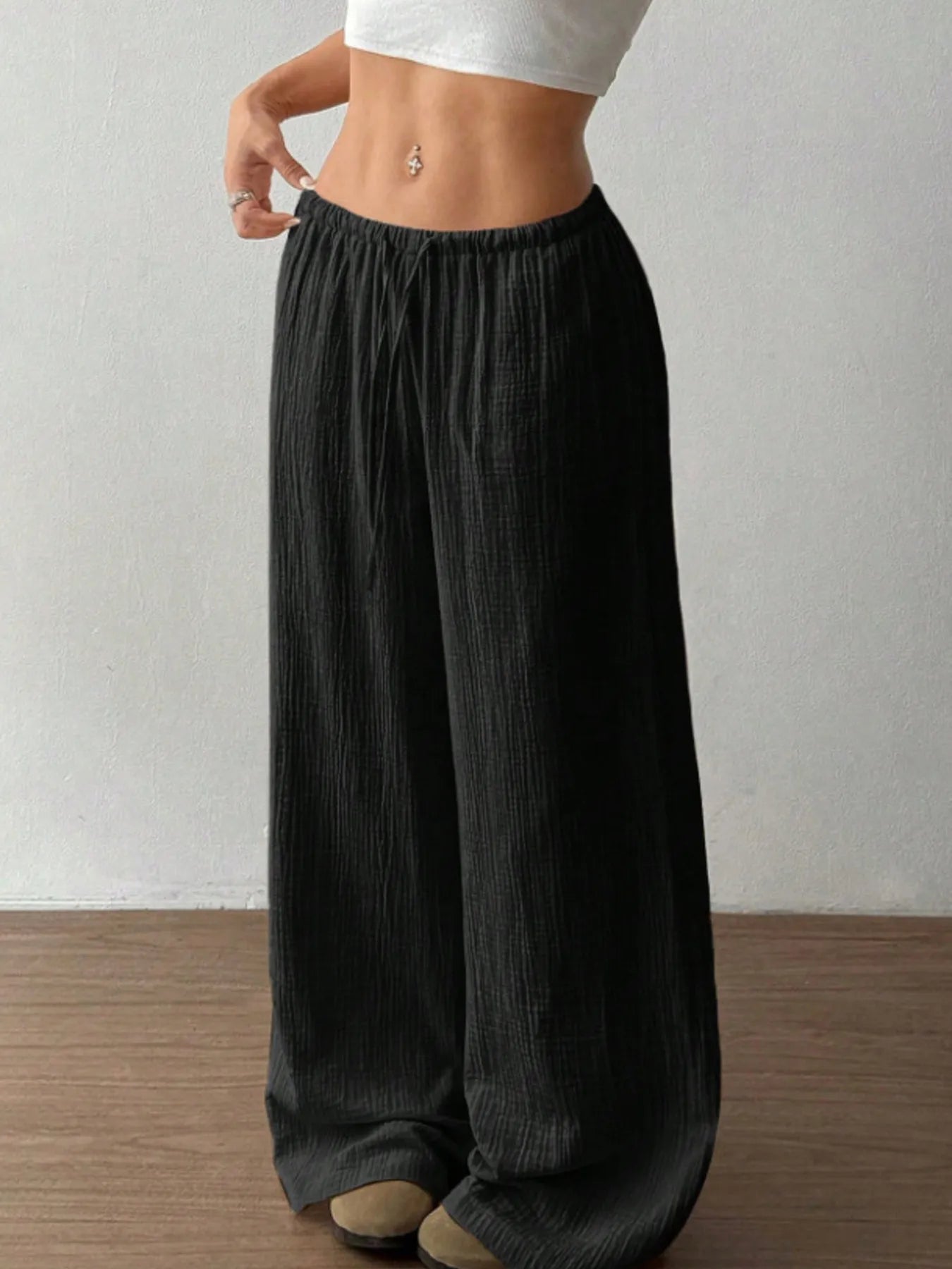 Person wearing black wide-leg pants against a plain background
