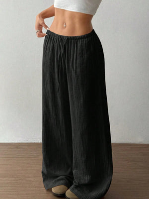 Person wearing black wide-leg pants against a plain background