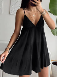 Woman wearing a black slip dress indoors with a neutral background