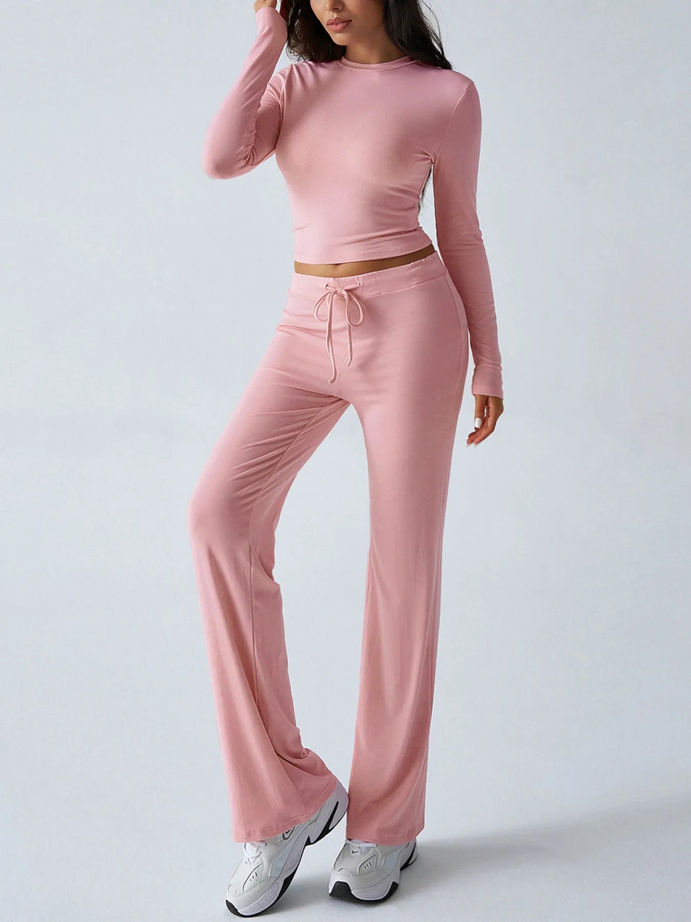 Person wearing a pink long-sleeve top and pants set on a white background