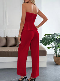Woman wearing a red strapless jumpsuit in a modern living room.