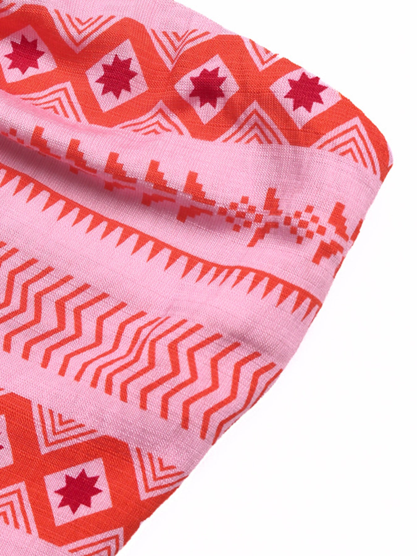 Close-up of pink fabric with red geometric patterns on a white background