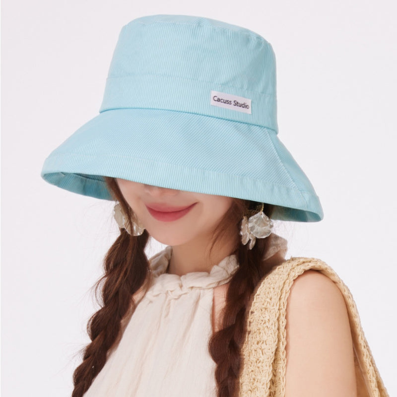 Light blue bucket hat worn by a person on a plain background