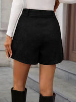 Person wearing black shorts with a neutral background