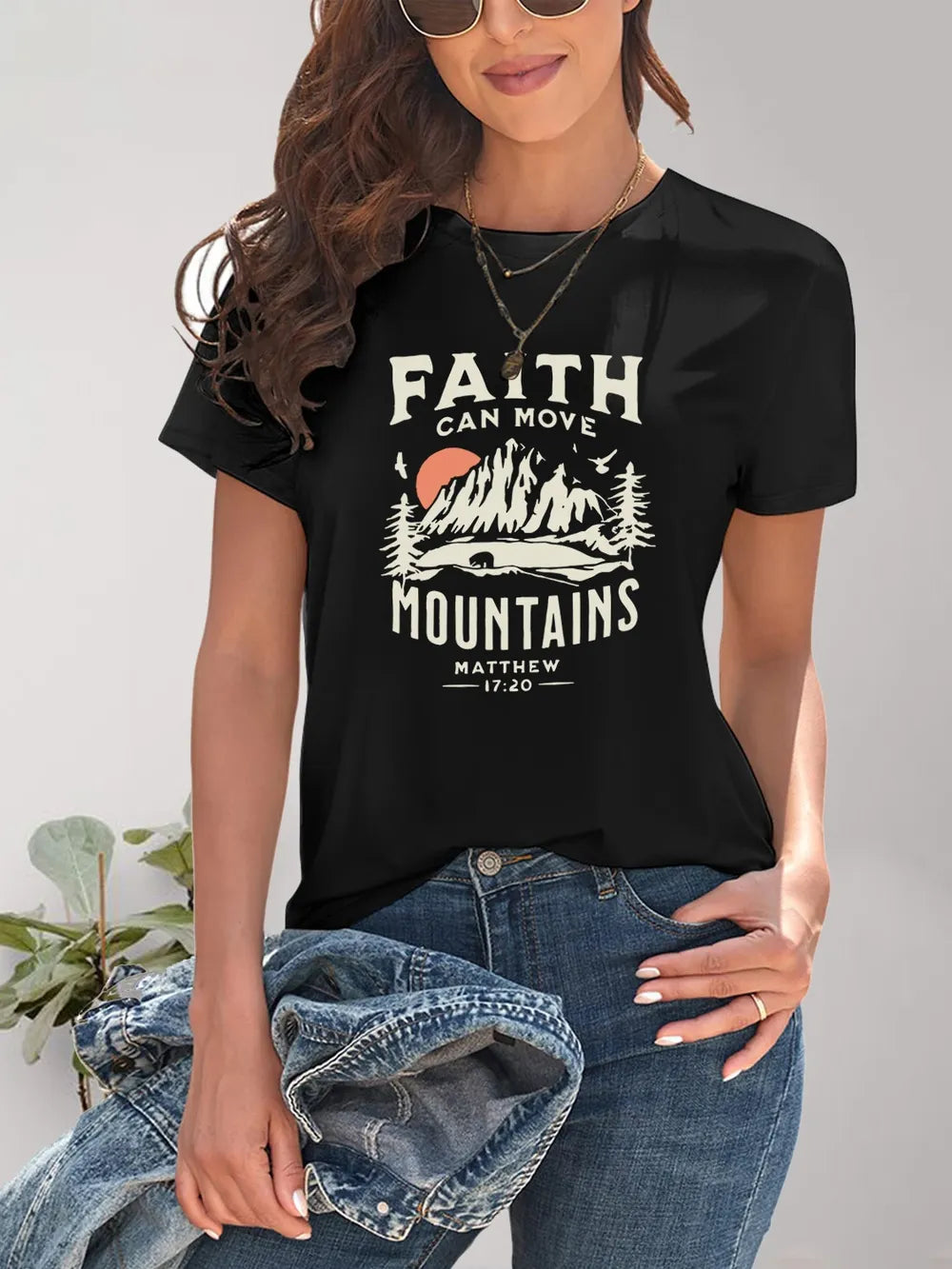 Person wearing a black t-shirt with 'Faith Can Move Mountains' graphic design.