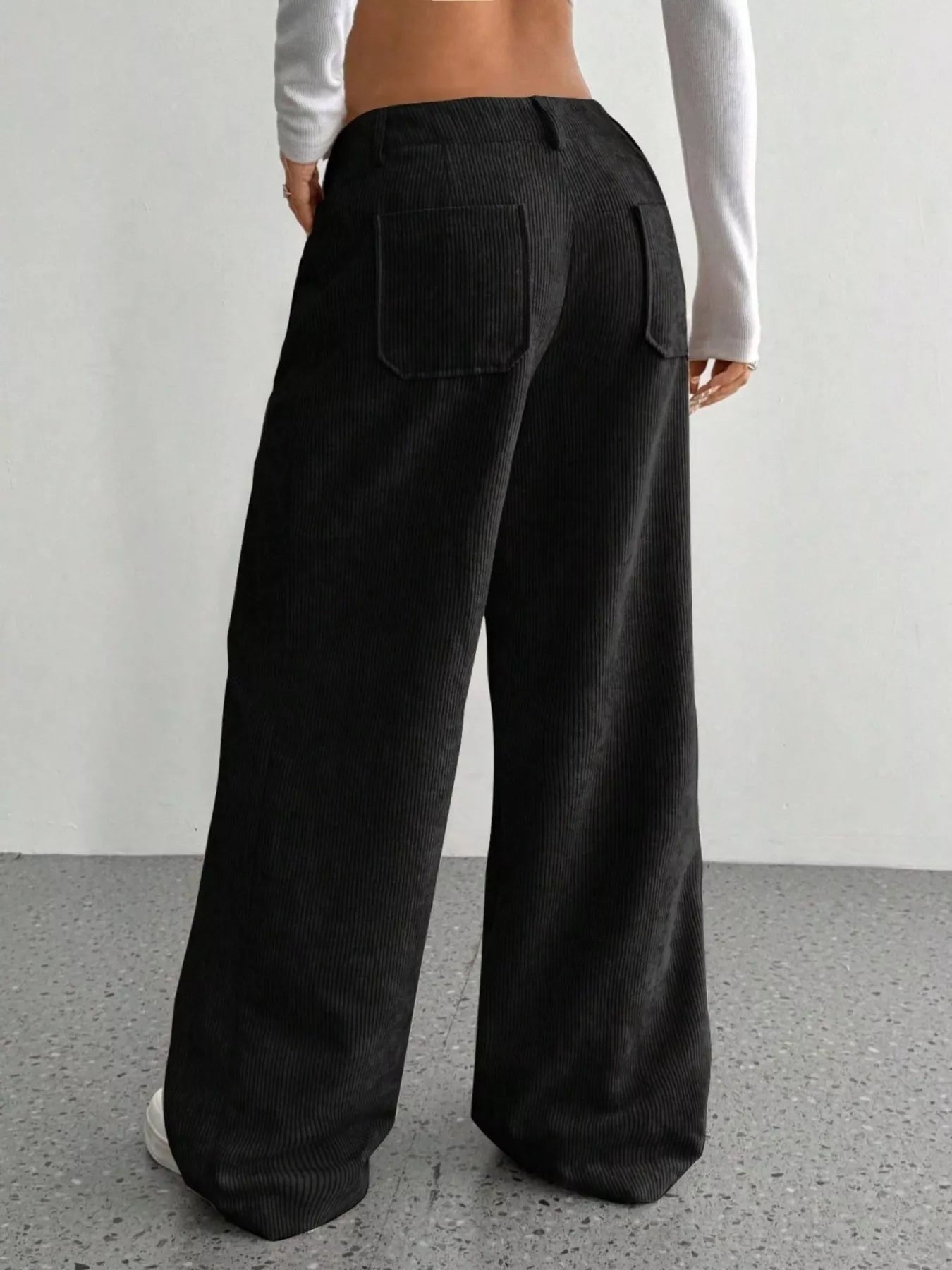 Person wearing black wide-leg pants with a plain background