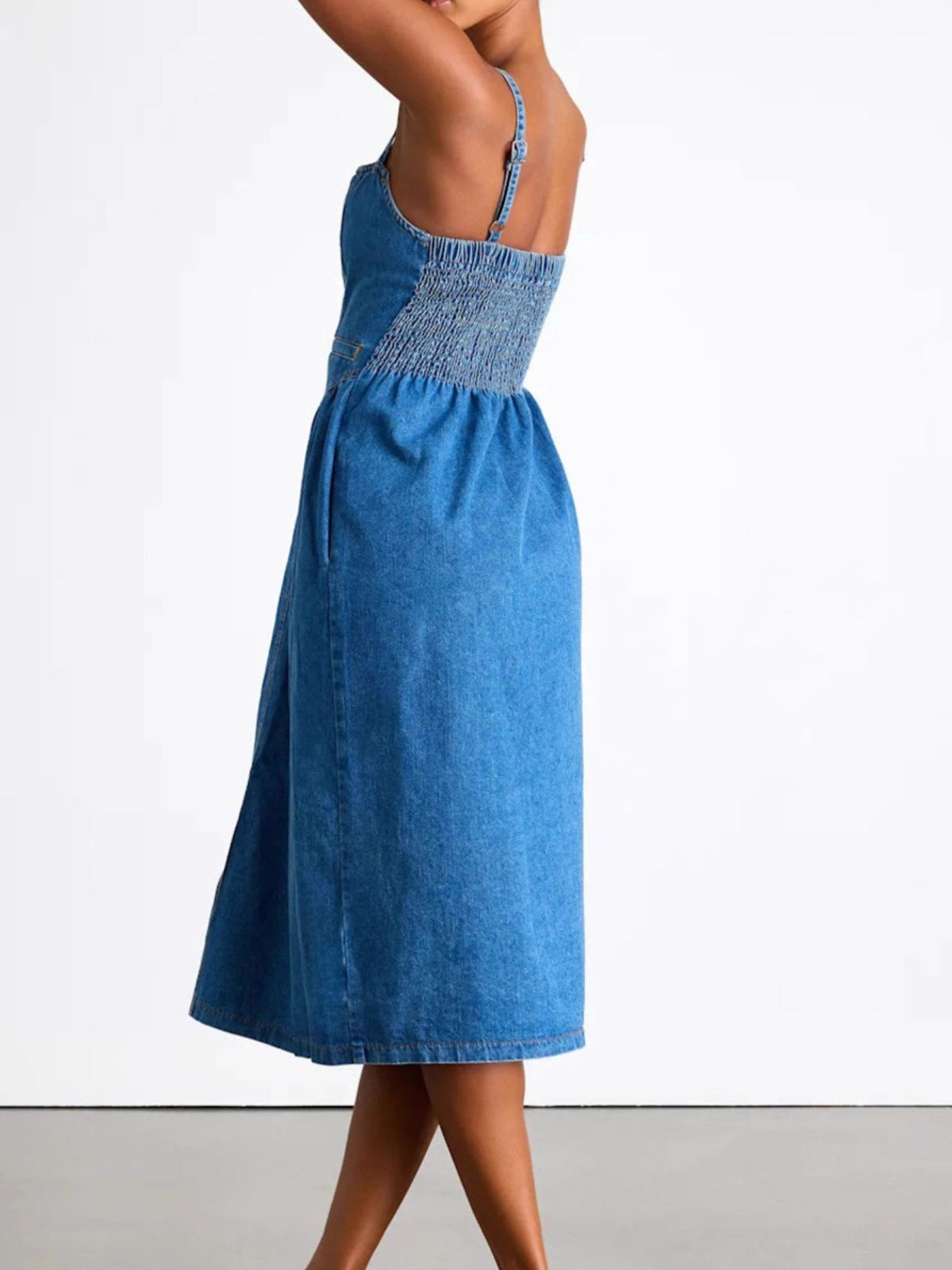 Blue denim dress with smocked waist on a white background