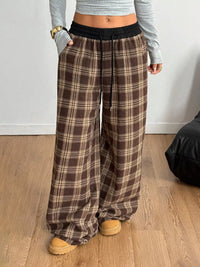 Person wearing plaid pants and a gray top on a wooden floor.