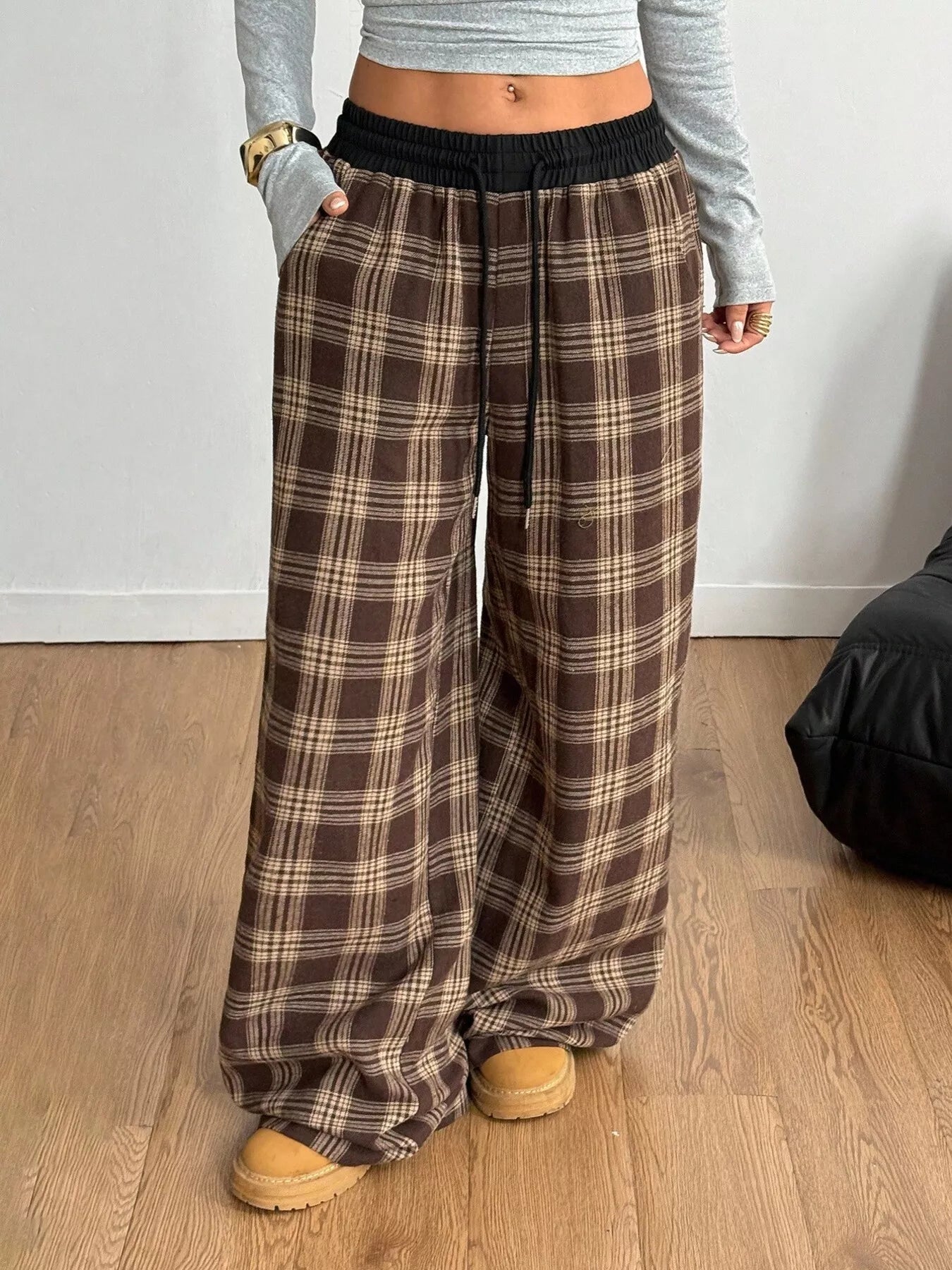 Person wearing plaid pants and a gray top on a wooden floor.