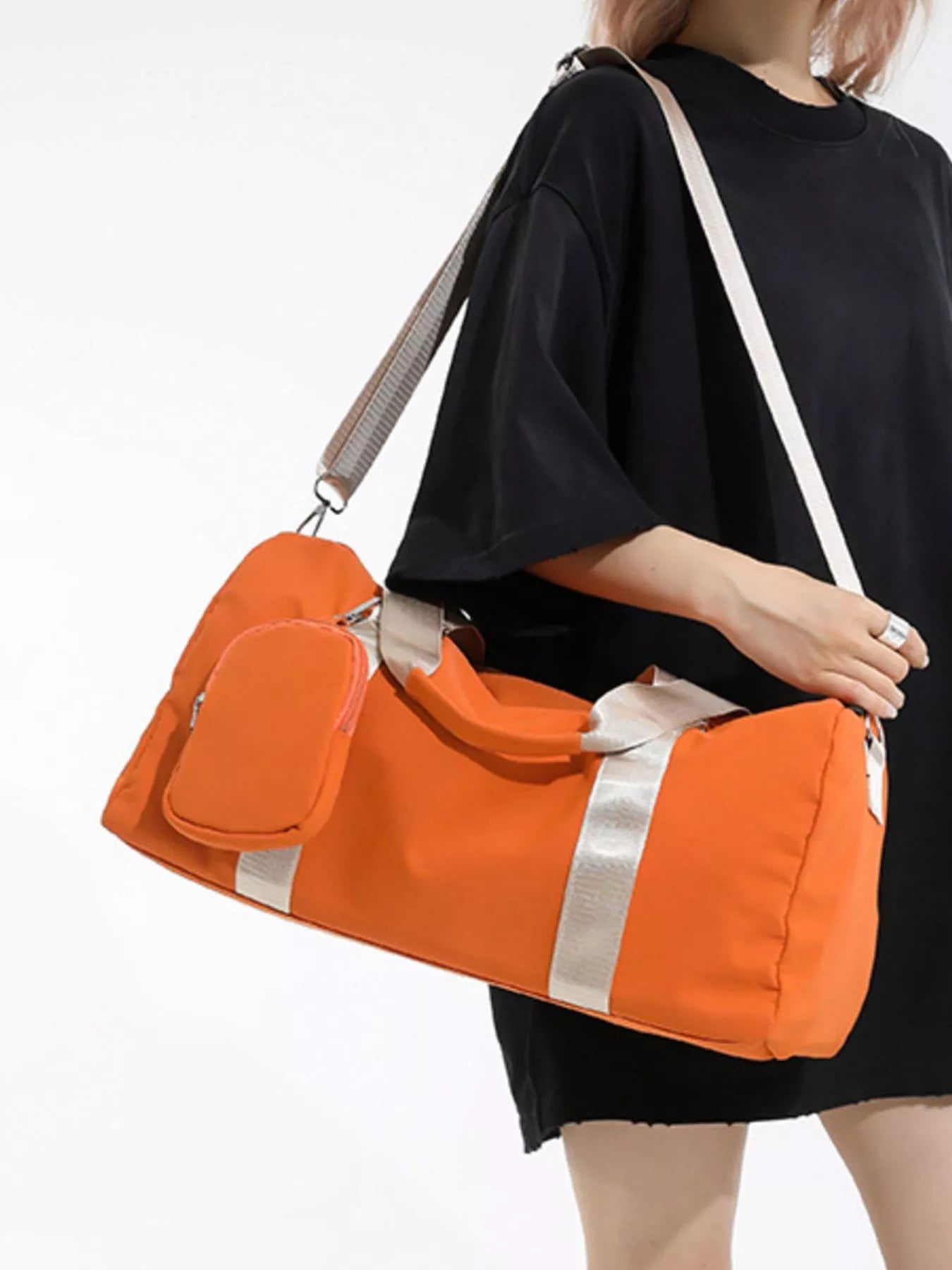 Person holding an orange duffel bag with a white background