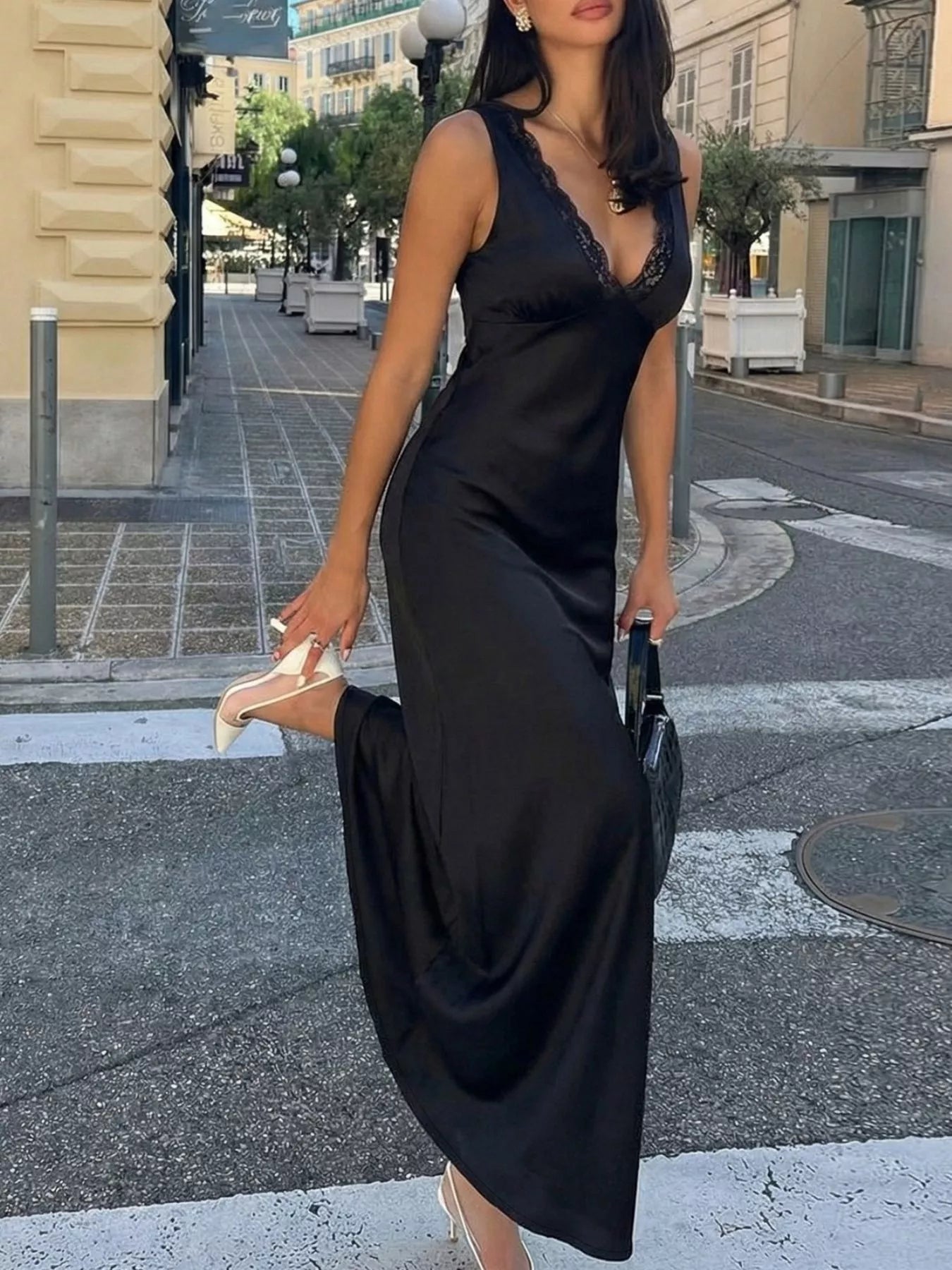 Woman in a black dress crossing a street in an urban setting