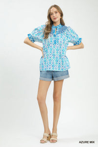 Woman wearing a blue patterned blouse and denim shorts on a white background
