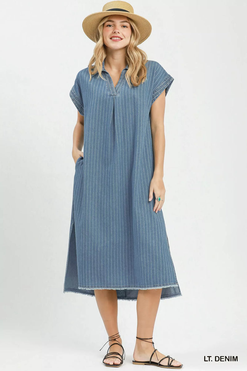 Woman wearing a light denim dress and hat on a white background