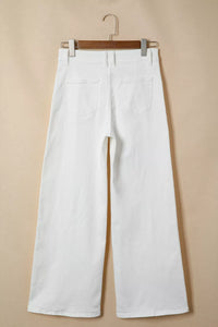 White pants hanging on a wooden hanger against a beige background