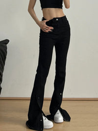 Person wearing black flared jeans and a black crop top on a plain background