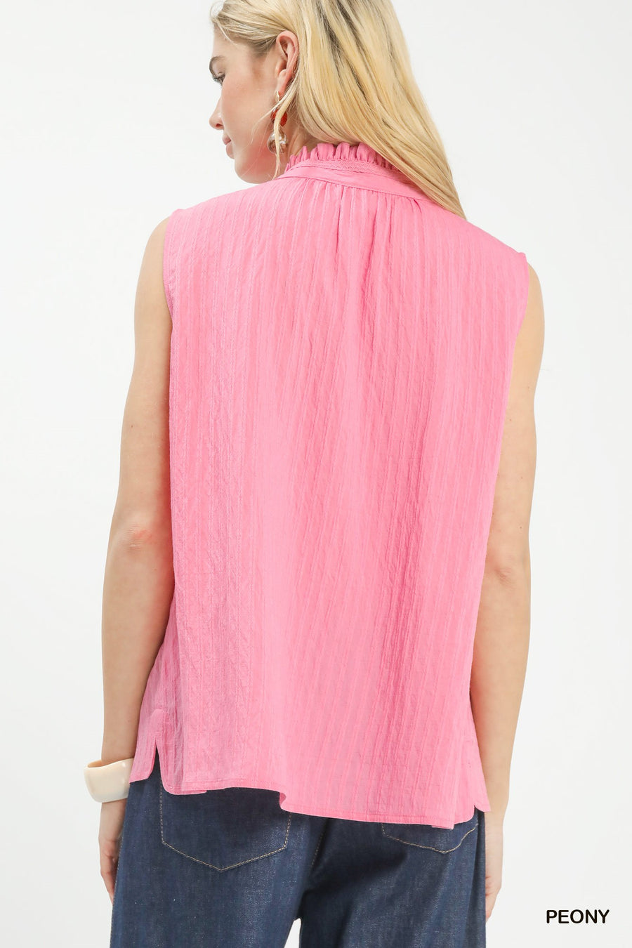 Woman wearing a pink sleeveless top with a plain background