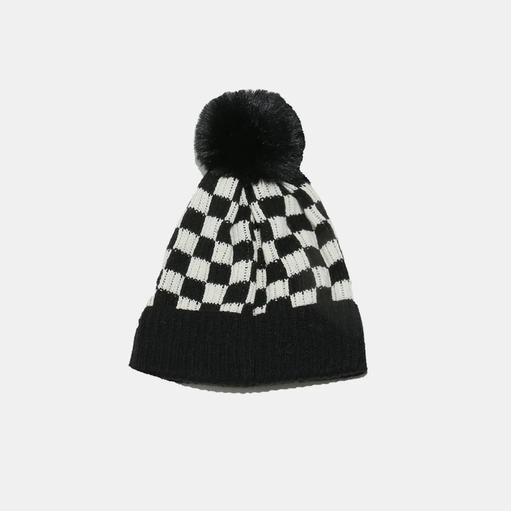 Black and white checkered beanie with a pom-pom on a light gray background