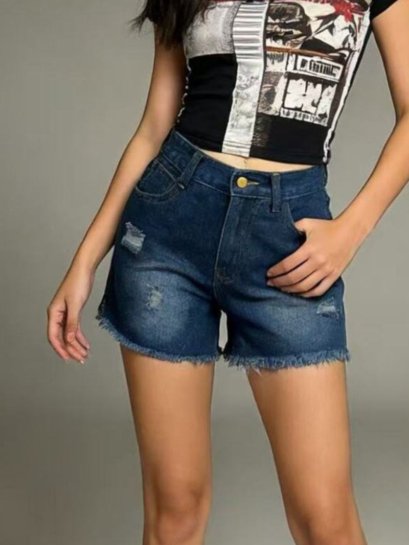 Person wearing a black and white patterned top with blue denim shorts on a gray background