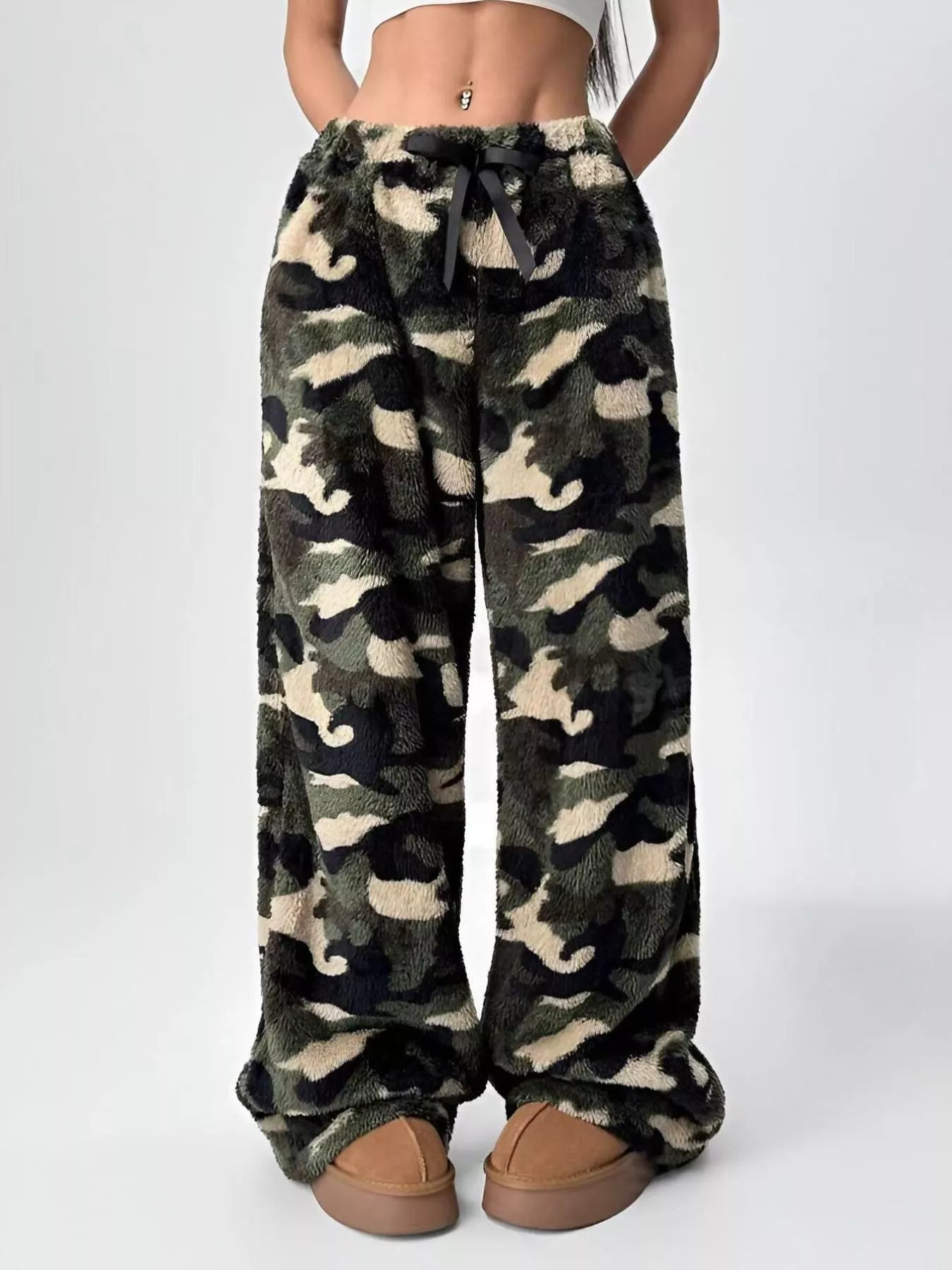Camouflage patterned pants worn by a person on a white background