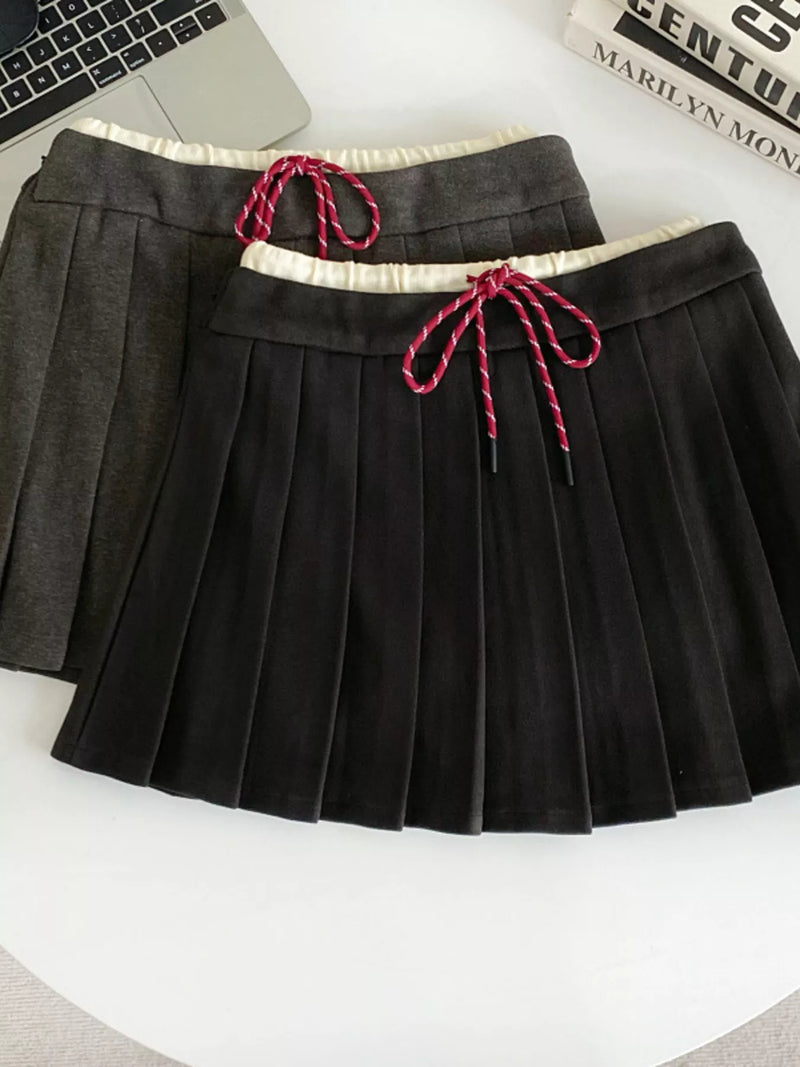 Black pleated skirt with red drawstrings on a white surface