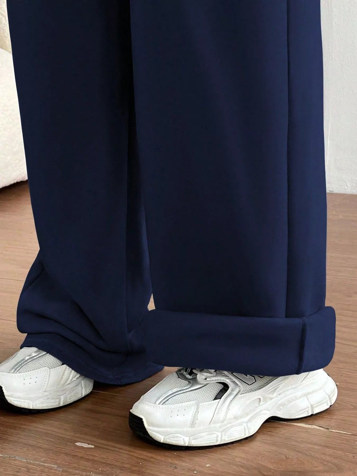 Navy blue pants with white sneakers on a wooden floor
