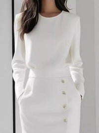 White long-sleeve dress with button details on a plain background