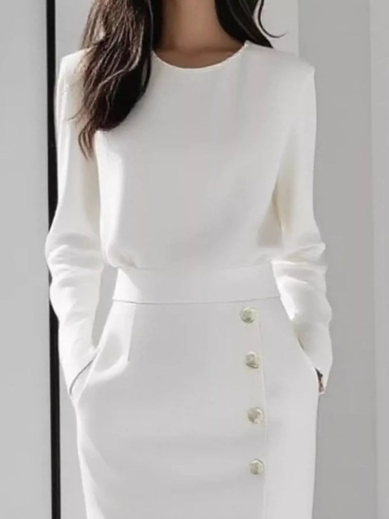 White long-sleeve dress with button details on a plain background