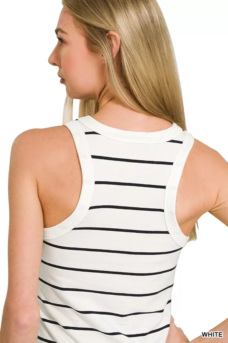 Woman wearing a white tank top with black stripes on a plain background