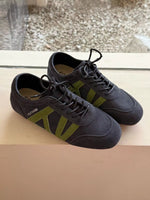 Pair of black sneakers with green accents on a reflective surface