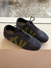 Pair of black sneakers with green accents on a reflective surface