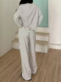 Person wearing a black and white striped outfit in a room with wooden floor and light green wall.