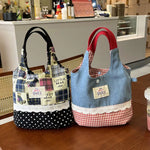 Two fabric bags, one plaid and polka dot, the other denim with red checkered accents, on a wooden surface.