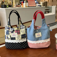 Two fabric bags, one plaid and polka dot, the other denim with red checkered accents, on a wooden surface.