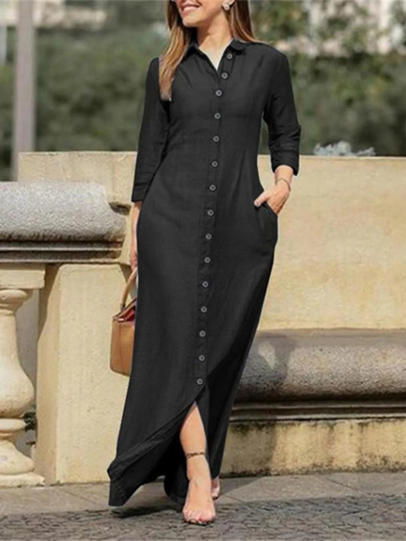 Woman wearing a black dress with a button-up front, standing outdoors.