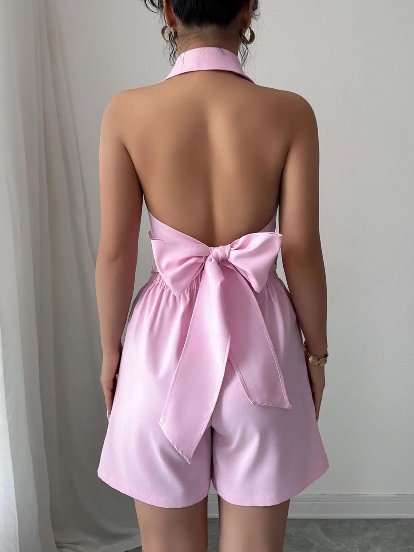 Pink romper with a bow detail on a plain background