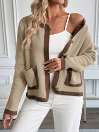 Woman wearing a beige cardigan with brown accents indoors.