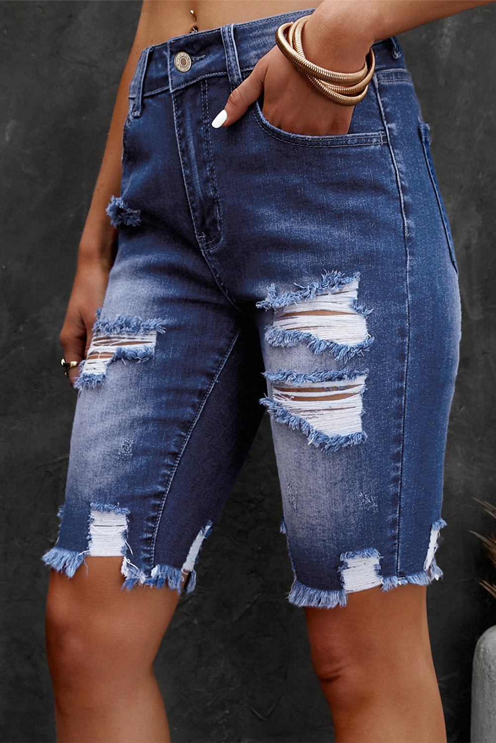 Denim shorts with distressed details on a dark background