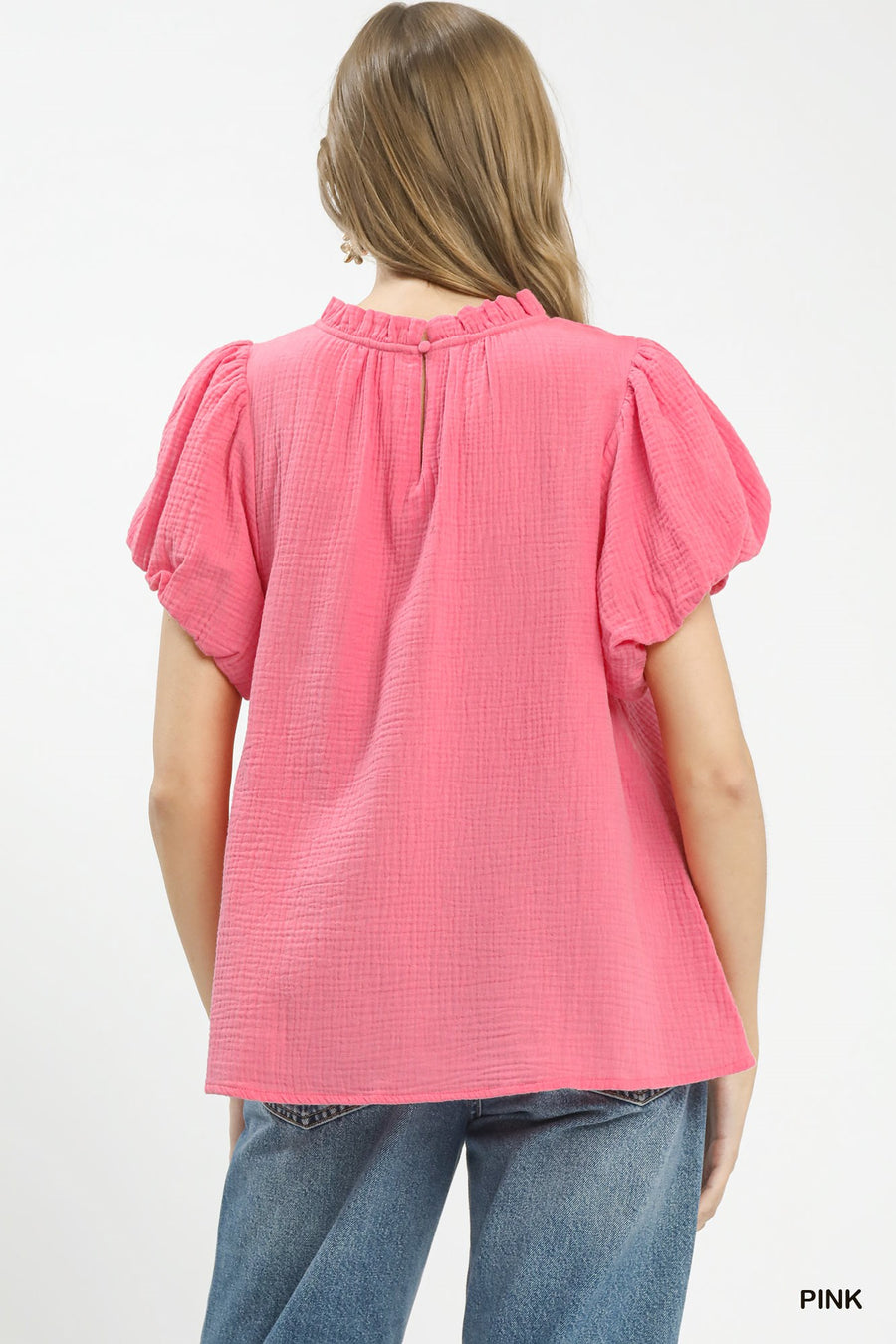 Woman wearing a pink textured top with ruffled sleeves on a white background