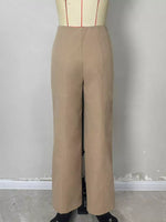 A pair of high-waisted, wide-leg trousers in a light tan/beige color, displayed on a dress form mannequin against a plain gray wall.