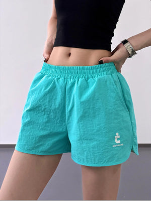 Teal athletic shorts with a logo on a plain background