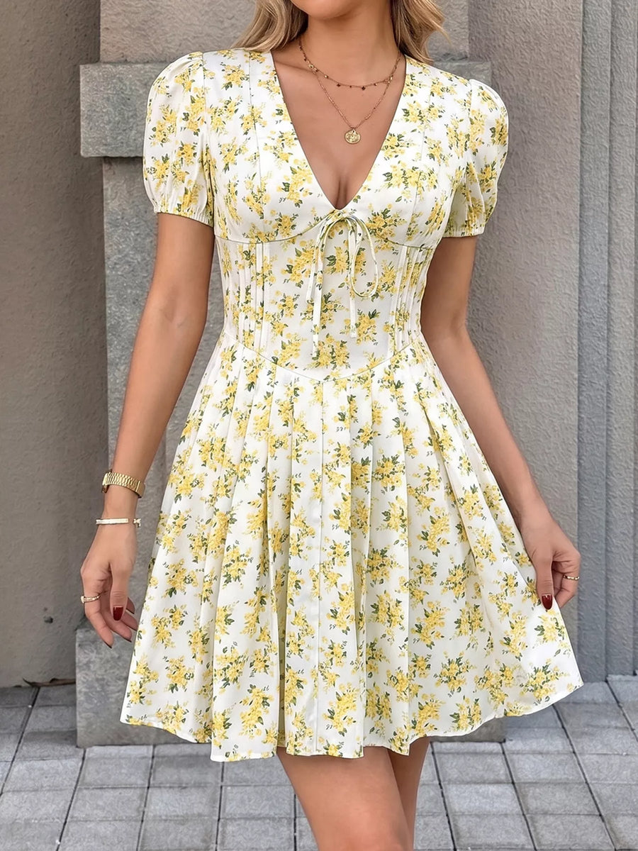 Woman wearing a yellow floral dress against a neutral background