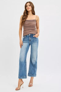 Woman wearing a brown tank top and blue jeans on a white background