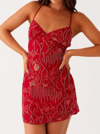 Red dress with floral patterns and embellishments on a white background