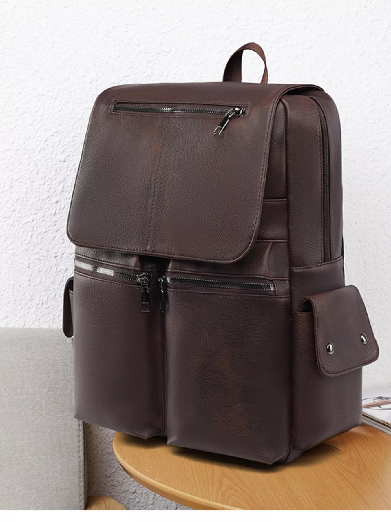Brown leather backpack on a wooden surface with a light gray background