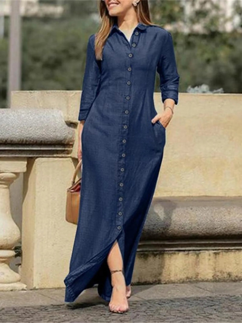 Woman wearing a long blue dress standing outdoors on stone steps.
