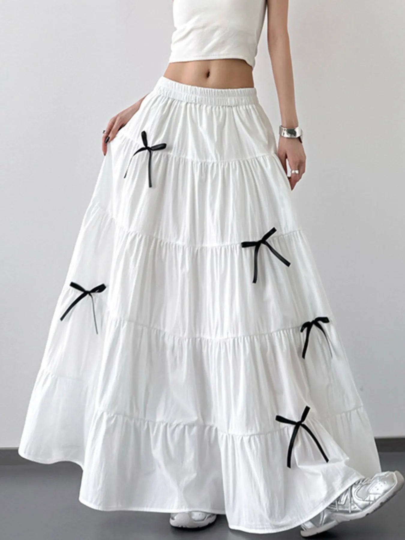 White tiered skirt with black bows worn by a person on a plain background