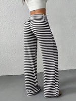 Black and white striped pants worn by a person against a plain background