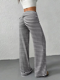 Black and white striped pants worn by a person against a plain background
