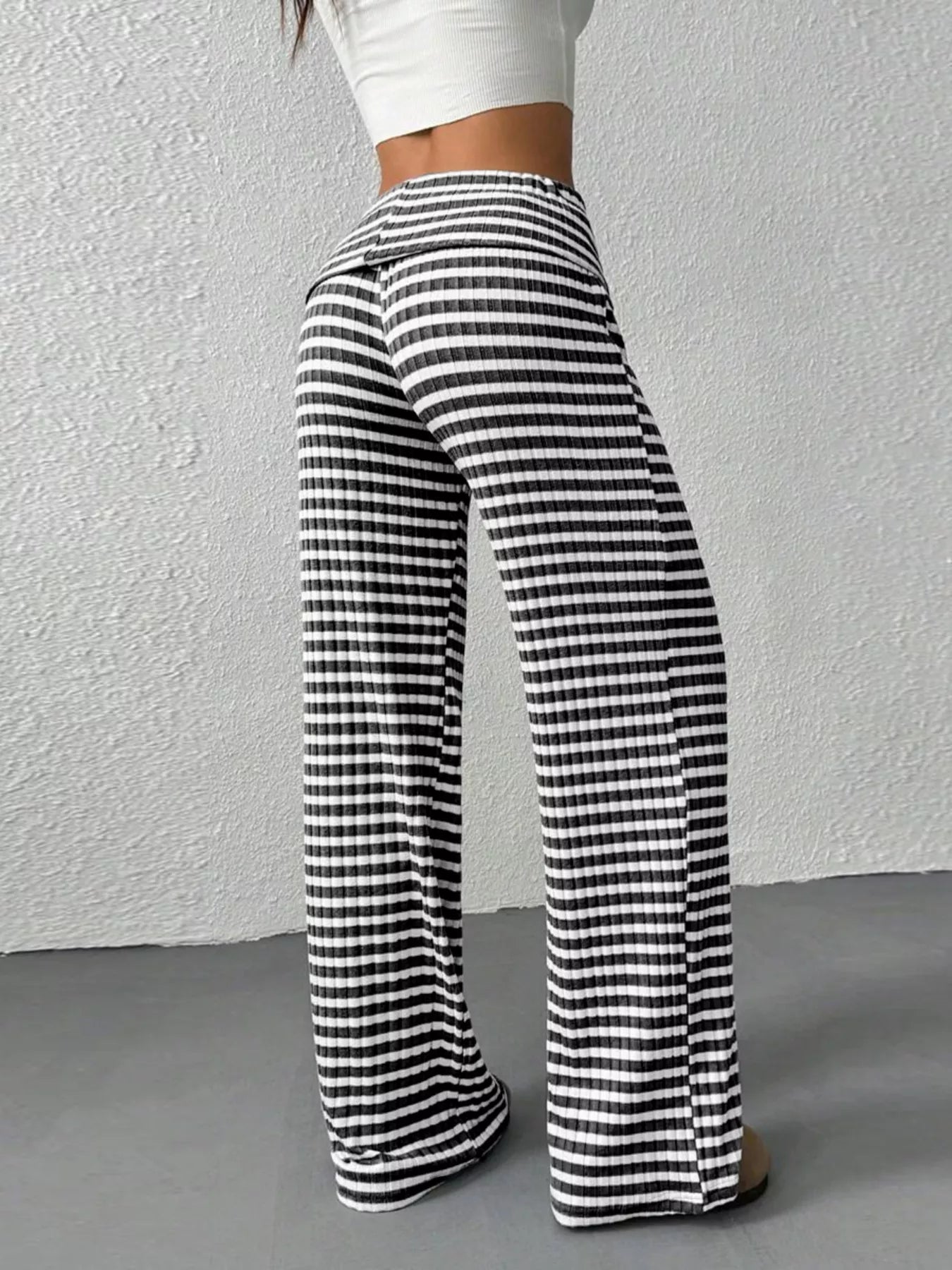Black and white striped pants worn by a person against a plain background