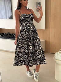 Woman taking a mirror selfie wearing a zebra print dress in a room.
